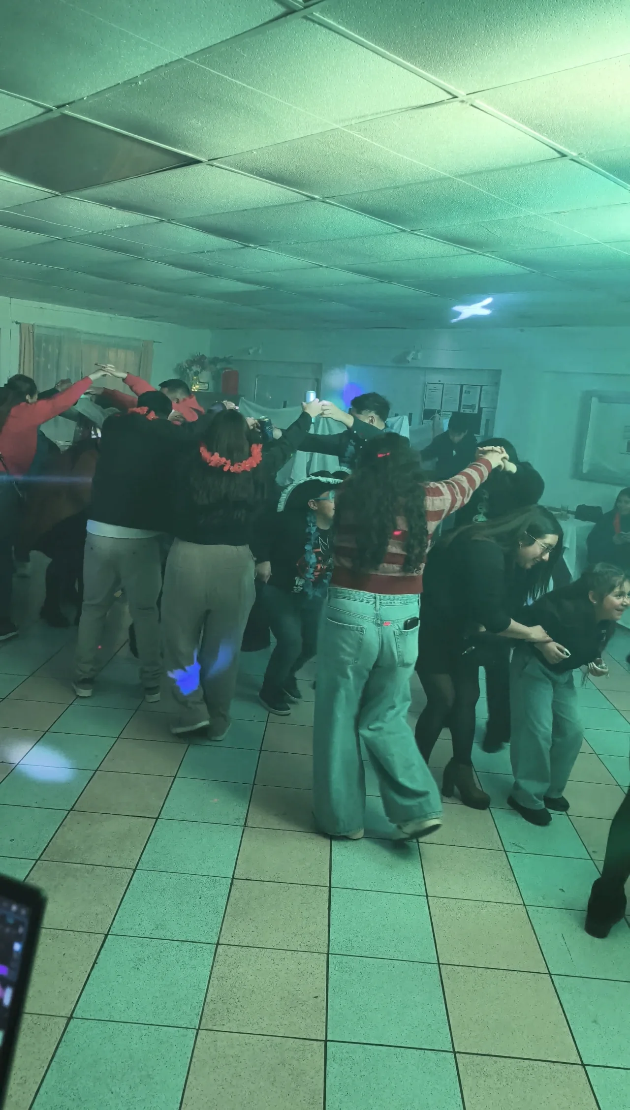Invitados bailando en grupo durante un baby shower con iluminación verde.