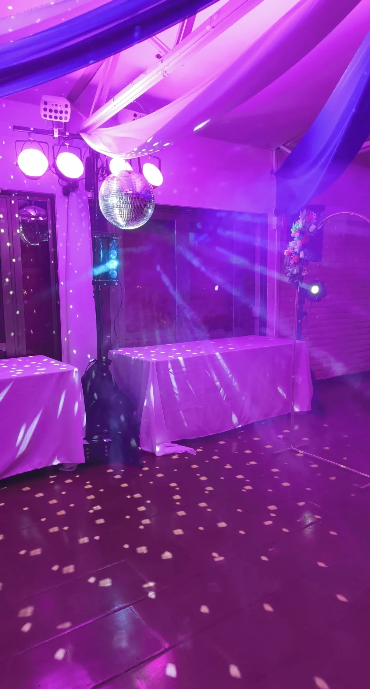 Montaje de iluminación violeta con bola disco en un baby shower.