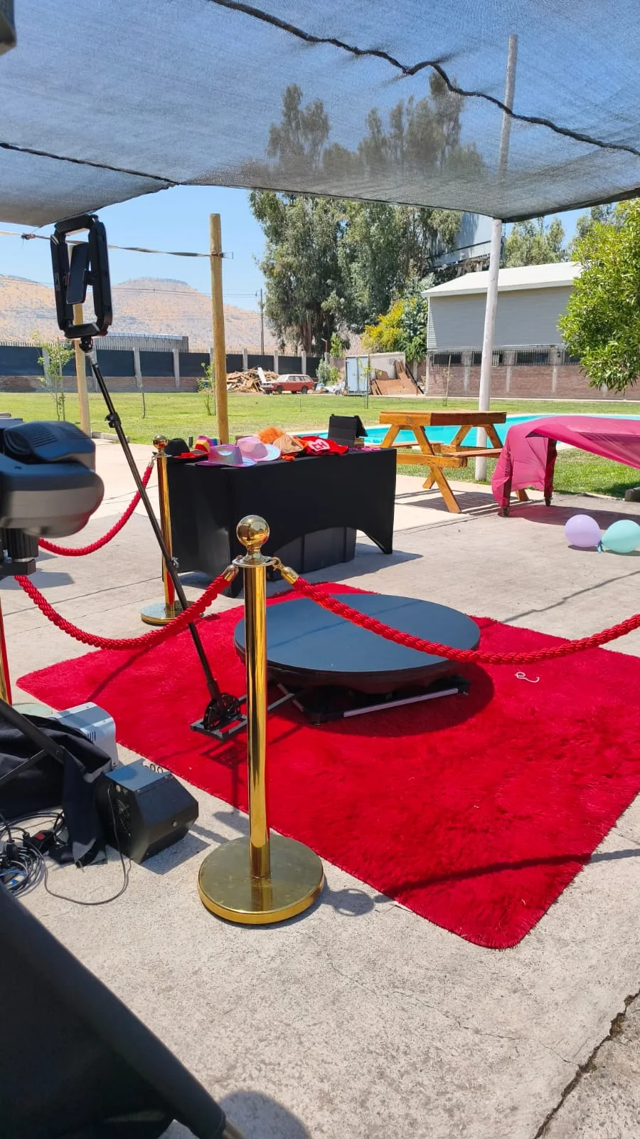 Plataforma 360 al aire libre con alfombra roja, separadores de fila y mesa de cotillón